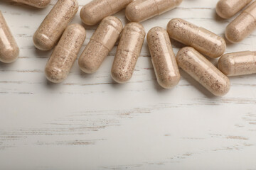 Gelatin capsules on white wooden table, flat lay. Space for text