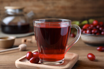 Glass cup of fresh dogwood tea and berries on wooden table