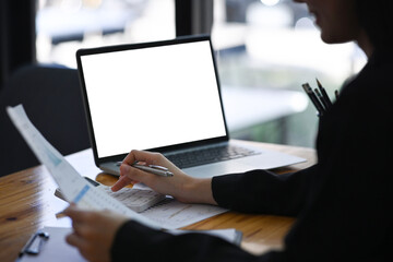 Cropped shot businesswoman working with laptop computer and checking reports in office.