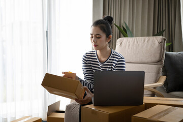 Small businesses owners checking online orders on computer laptop and preparing parcel for delivery to customer