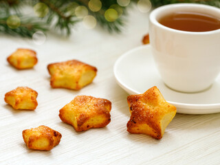 Christmas and happy new year card with cup of tea, fir branch and gingerbread in shape of stars on white wooden background, copy space, side view