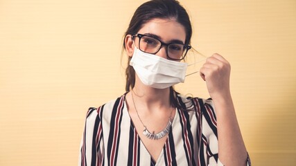 Young woman take off face mask removing from face showing concept of the end of quarantine and...