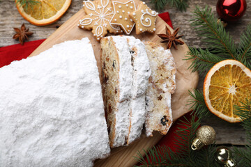 Traditional Christmas Stollen with icing sugar on wooden table, flat lay