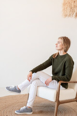 Attractive young woman sitting on the chair in light and airy interior