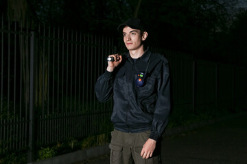 Male security guard with flashlight at night