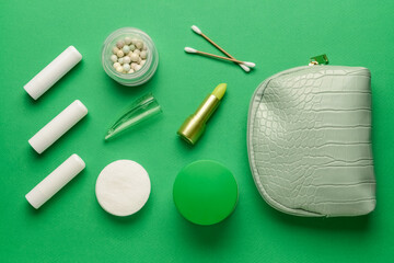 Bag, care cosmetics, cotton buds and cotton pads on green background