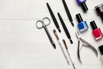 Manicure equipment and nail polishes on light wooden background