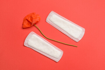 Menstrual pads and poppy flower on red background