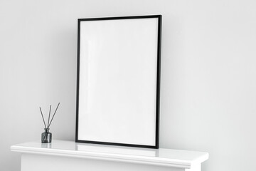 Blank frame with reed diffuser on mantelpiece near light wall
