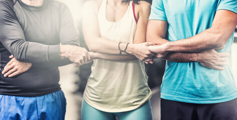 A team of two men and a woman in the middle in sportswear hold hands as a symbol of team spirit and...