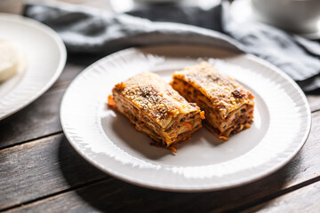 Two pieces of lasagna served on a white plate topped with grated parmesan cheese