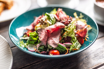 Thinly sliced roastbeef served on a crunchy slad with carrots, cherry tomatoes and radishes