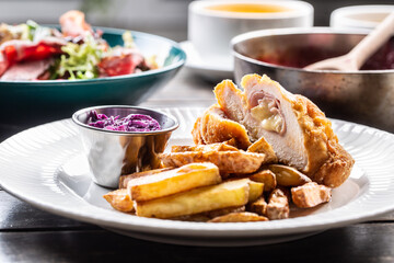 Chicken cordon bleu with ham and cheese inside served with fried potato wedges and red cabbage salad