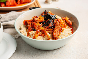 Bowl with delicious oatmeal, beef stew and prunes on light table