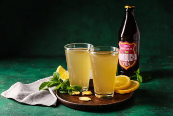 Glasses and bottle of natural kombucha on color background