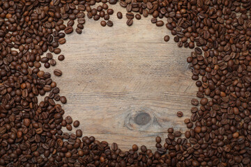 Frame roasted coffee beans on wooden table, flat lay. Space for text