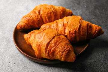 Plate with delicious croissants on grunge background