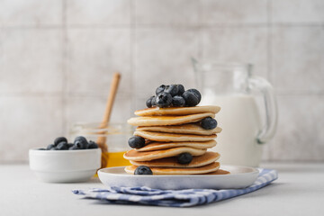 Homemade pancakes with blueberries in stack on light table with tile background