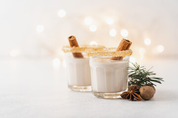 Eggnog with cinnamon and nutmeg for winter holidays. Christmas traditional eggnog in glasses on white background 