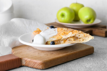 Plate with piece of tasty apple strudel on light background