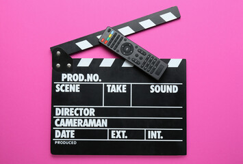 Fototapeta na wymiar Modern TV remote control and clapperboard on pink background