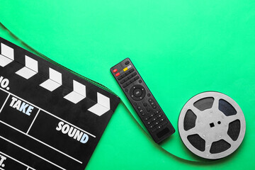 Modern TV remote control with film reel and clapperboard on green background