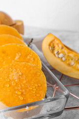 Baking dish with fresh pumpkin pieces on light background, closeup