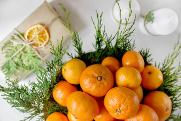 Fototapeta na wymiar Christmas composition with thuja twigs. Tangerines with wrapped gifts on light background.