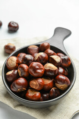 Obraz premium Frying pan with chestnuts on white background, closeup