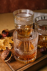 Wooden board with glasses of chestnut whiskey on table