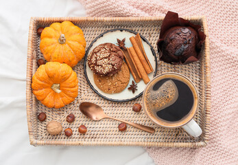 Cup of tasty pumpkin coffee, cookies and muffin in white fabric background