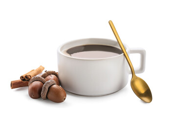 Cup of coffee with acorns and cinnamon on white background