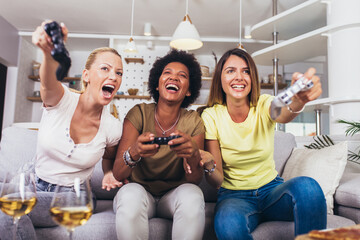 Portrait of happy women friends playing video games at home.
