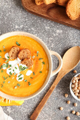 Pot with delicious pumpkin cream soup on grey background