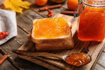Toasts with sweet pumpkin jam on wooden background