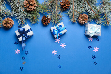 Christmas composition with gift boxes, pine cones and fir branches on blue background