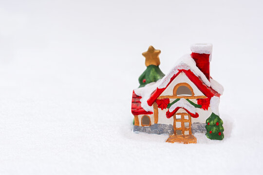 Christmas house snow. Christmas colorful horizontal postcard copy space. The concept of a holiday, a festive mood. A fabulous atmosphere, a toy clay red-green house on fluffy snow. Happy New Year