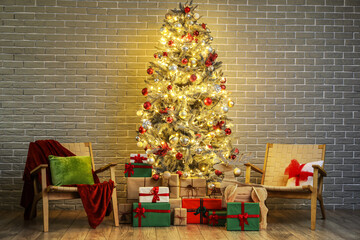 Beautiful Christmas tree with glowing lights, gifts and chairs near brick wall