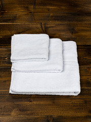 stack of white towels of different sizes on wooden background