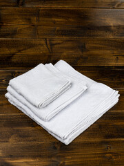 stack of white towels of different sizes on wooden background
