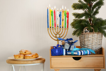 Menorah with donuts and gifts for Hanukkah celebration in room
