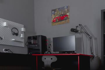 Workplace of a schoolboy teenage boy with a computer for games and learning in black and red colors