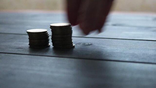A woman puts columns of coins, a stack of cash collapsed. The concept of the growth and fall of the currency exchange rate. Selective focus. Appreciation and depreciation of money.