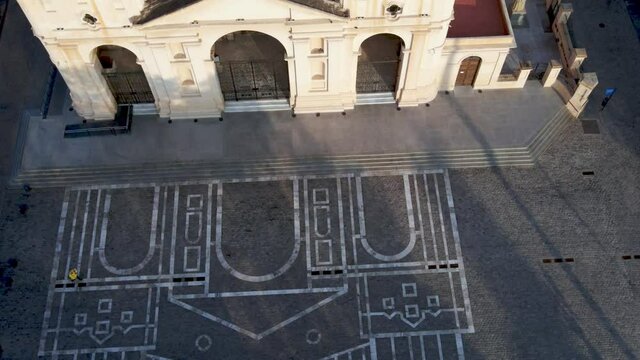 Aerial birds eye view capturing quiet and empty San Martin plaza at the front of old cathedral of Cordoba with building blueprint projected on the ground, establishing shot