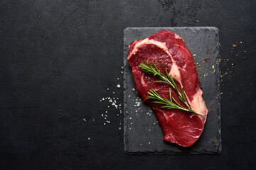 Raw organic rib eye steak with spices . Top view with copy space.