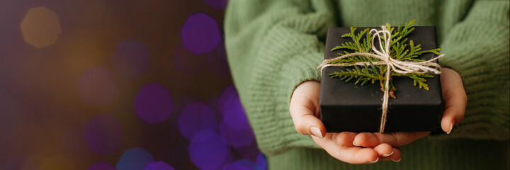 Female hands holding nice gift box, blured bokeh light on background.