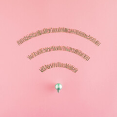 Wireless network symbol made of  pine needles shaped into WiFi symbol on a pastel pink background. Minimal internet technology idea. Flat lay winter concept. Christmas and december inspiration.