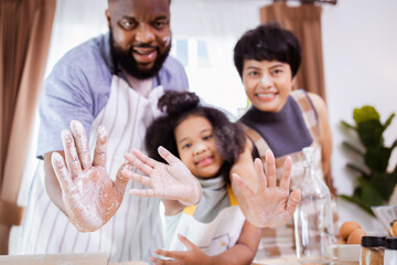 Happy African American family enjoy together while prepare the flour for making cookies at home. Look at camera.