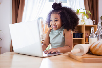 Happy African American girl use laptop and having fun while preparing cookie dough at home.