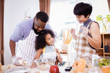 Happy African American father and daughter having fun while preparing cookie dough at home. happy family time.
